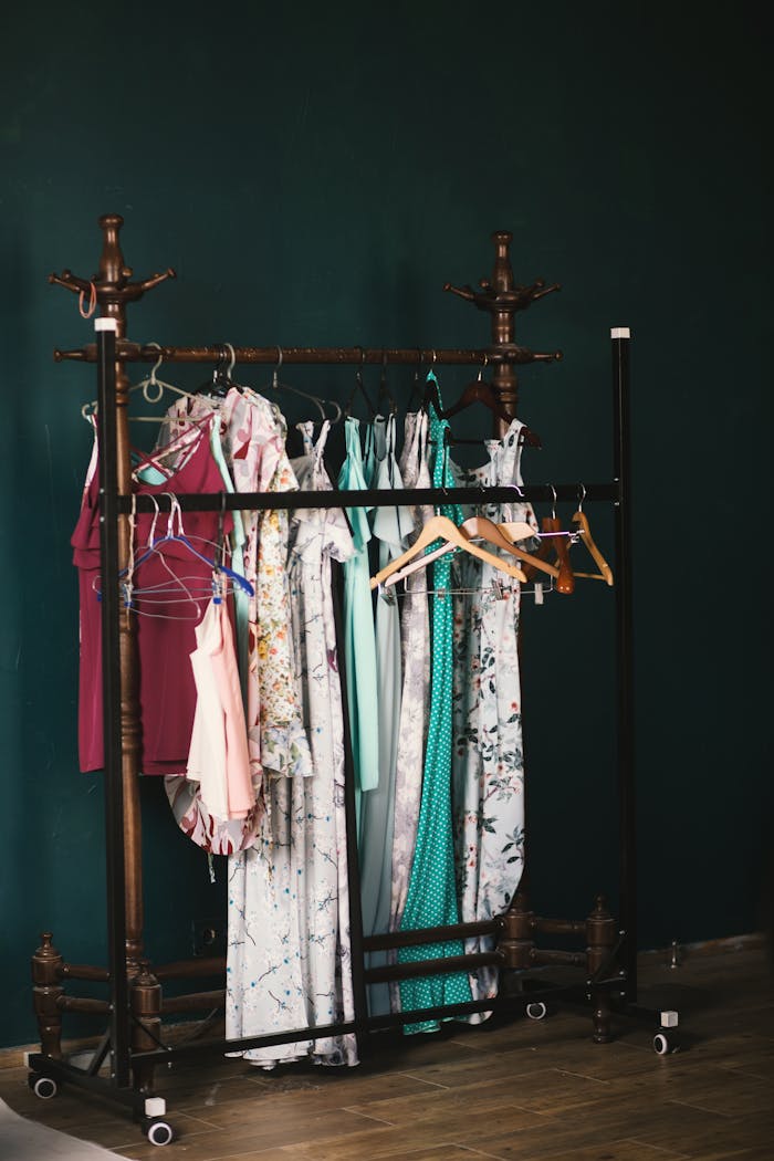 hero-gallery-03 A stylish collection of dresses on a wooden clothes rack against a dark wall, creating a chic aesthetic.