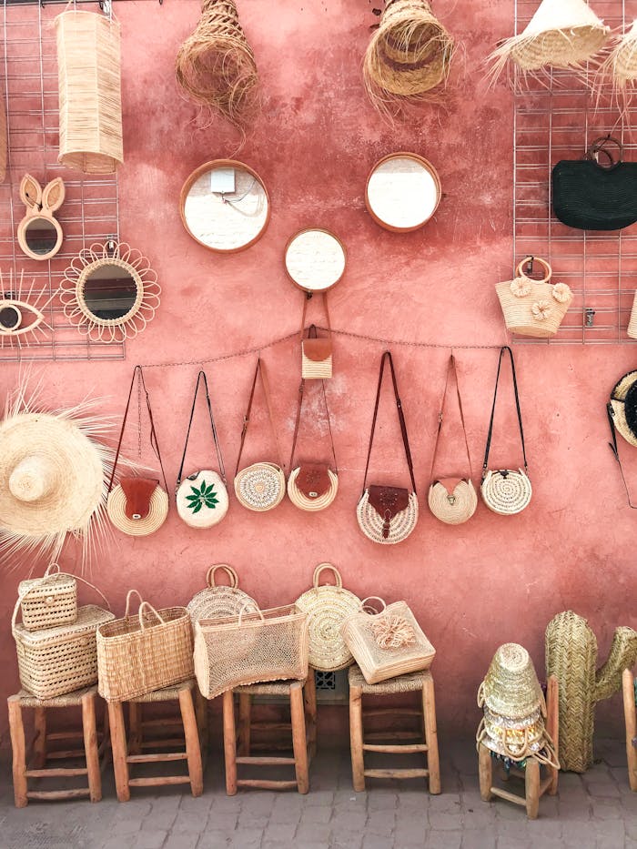 gallery-img-01 Aesthetic display of handmade wicker and straw accessories against a textured pink wall.