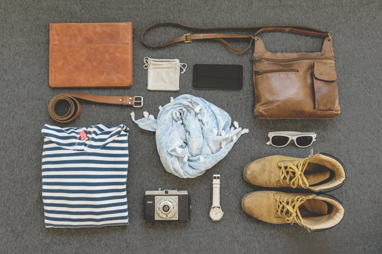 hero-gallery-01 Vintage travel essentials flat lay with leather bags, shoes, camera, and clothing.