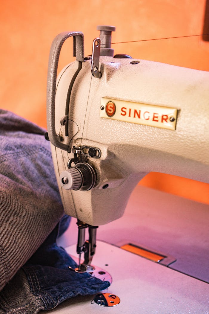 cta-02 Detailed view of a Singer sewing machine working on denim fabric with precision.